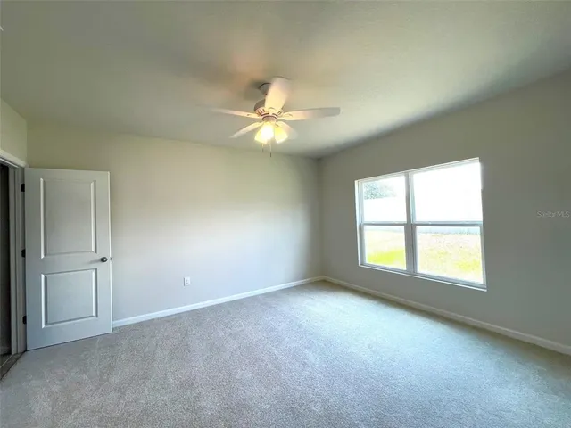 an empty room with windows and ceiling fan