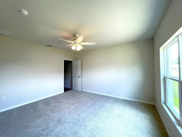 an empty room with a chandelier fan and windows