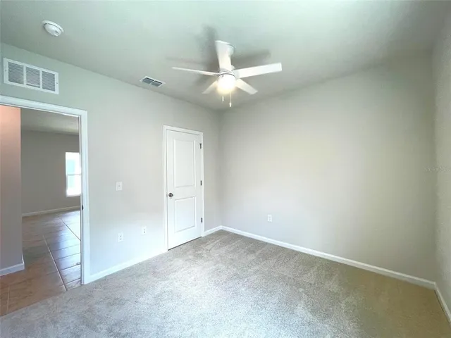 an empty room with closet and a ceiling fan