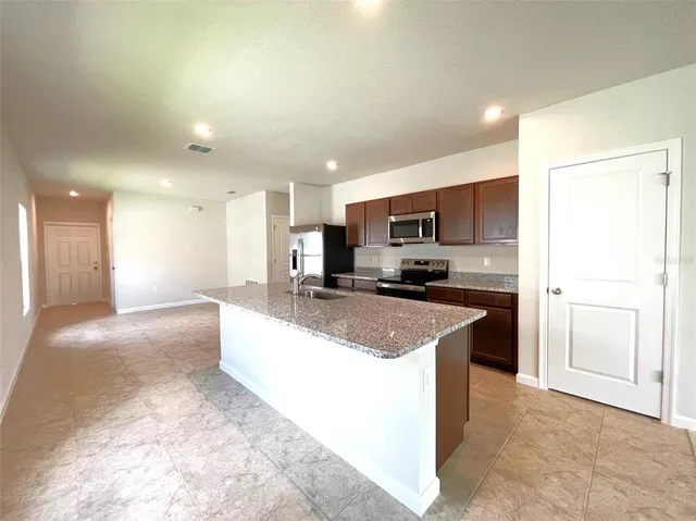 a large kitchen with stainless steel appliances kitchen island a stove a refrigerator a sink a microwave and cabinets