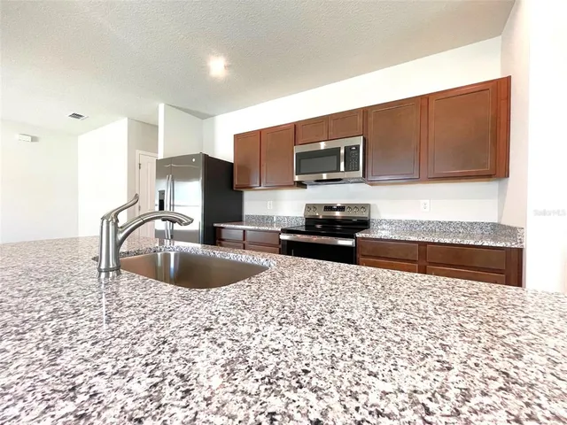 a kitchen with stainless steel appliances granite countertop a sink a stove top oven and granite counter tops