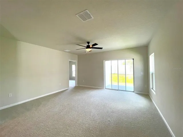 an empty room with windows and chandelier fan
