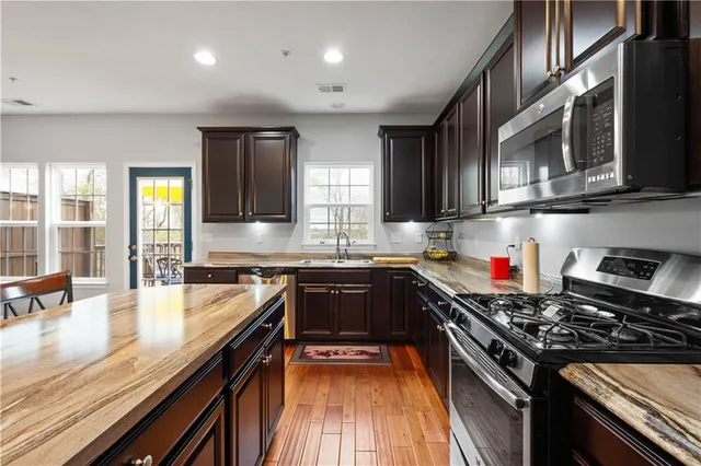a kitchen with stainless steel appliances granite countertop a stove a sink and a microwave