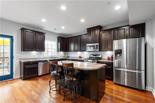 a kitchen with kitchen island granite countertop stainless steel appliances cabinets a sink and a counter top space