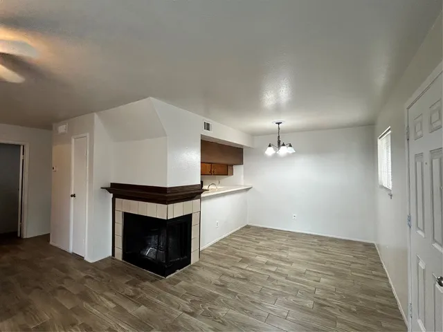 a view of an empty room with wooden floor and a fireplace