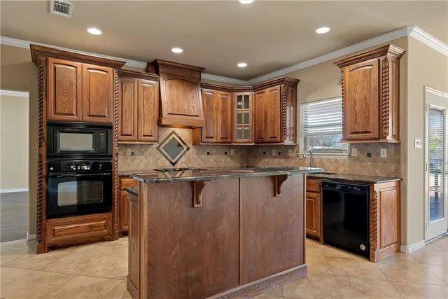 a kitchen with kitchen island granite countertop a stove top oven sink and cabinets