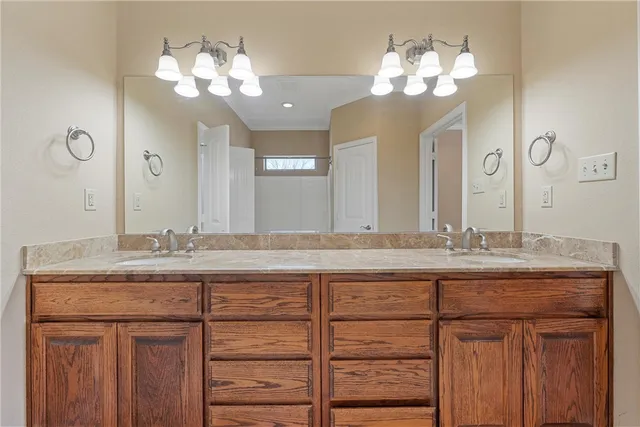 a bathroom with a granite countertop double vanity sink and a mirror