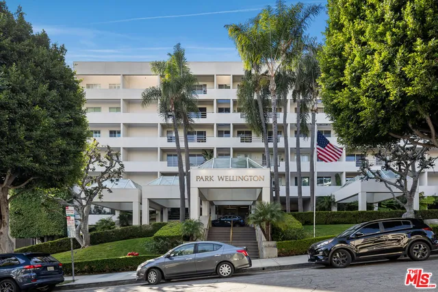 a car parked in front of a building with large trees