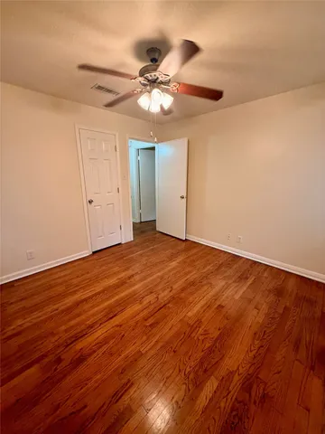 a view of a room with wooden floor and a ceiling fan