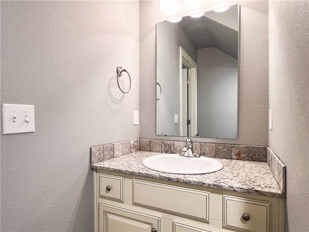 1275 North Rupple Road Fayetteville, AR 72704 - Photo 7 of 20 Bathroom vanity featuring a granite-style countertop, integrated white sink, and chrome faucet