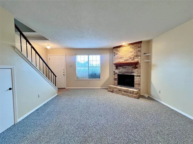 a view of an empty room with a fireplace and a window