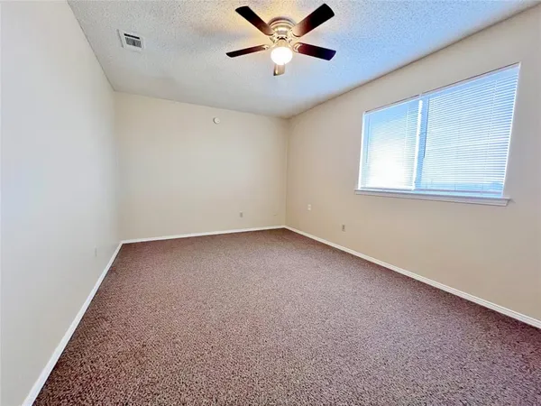 an empty room with a window and a ceiling fan