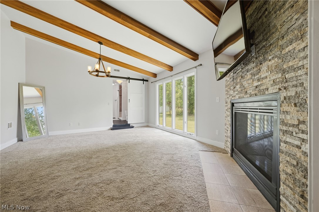 8160 Joyce Road Broadview Heights, OH 44147 - Photo 20 of 45 Vaulted ceiling with exposed wood beams, stone-clad fireplace, large picture windows, and light neutral carpeting
