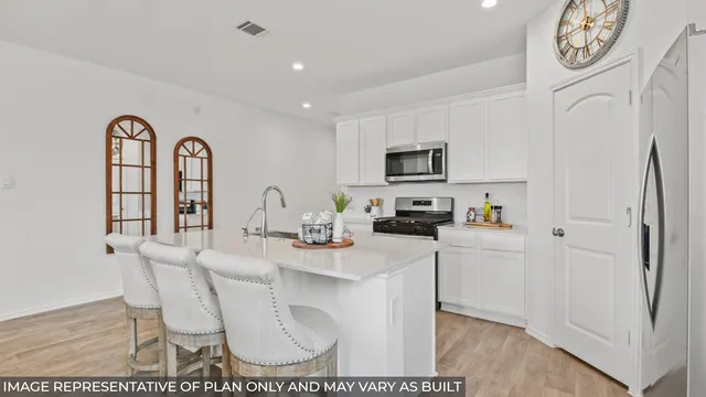 a kitchen with stainless steel appliances granite countertop a stove a sink a refrigerator a microwave a dining table and chairs with wooden floor