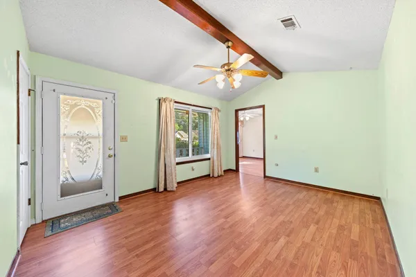 a view of an empty room with wooden floor and a window