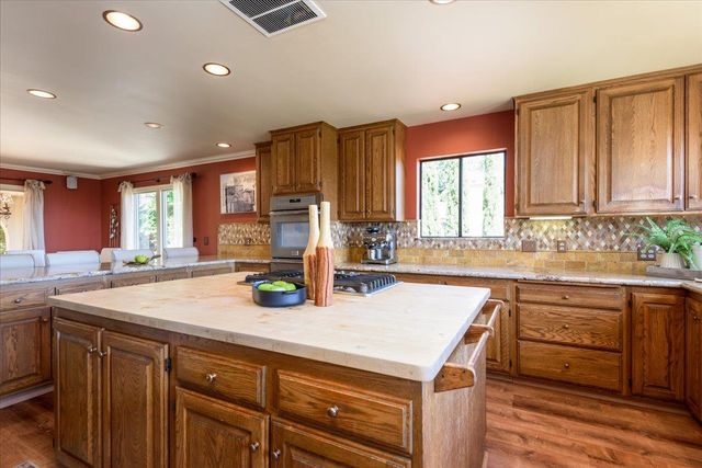 a kitchen with stainless steel appliances granite countertop a refrigerator a sink dishwasher and cabinets with wooden floor