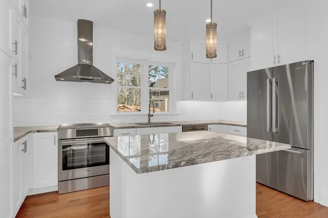 a kitchen with stainless steel appliances granite countertop a stove a refrigerator and a sink with wooden floor