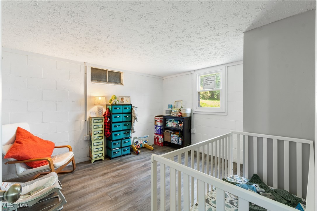 271 Sterling Avenue Rittman, OH 44270 - Photo 21 of 31 Bedroom with wood finished floors, a textured ceiling, a crib, and concrete block wall