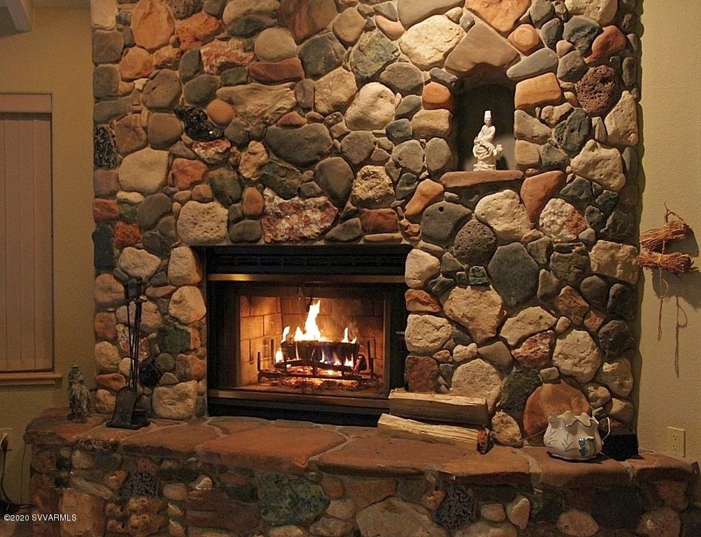 2275 Corral Road Sedona, AZ 86336 - Photo 19 of 30 a living room with a fireplace wooden floor and a couch