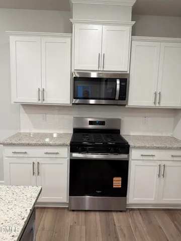 a kitchen with cabinets stainless steel appliances and wooden floor