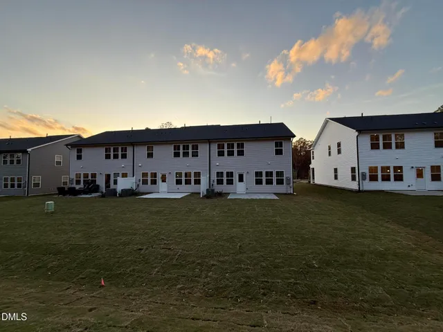 a view of a big house with a big yard potted plants and large tree