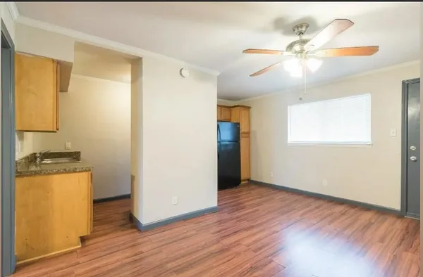 a view of a room with wooden floor a ceiling fan and windows