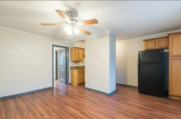 a view of an empty room with wooden floor and a ceiling fan