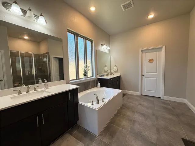 a bathroom with a tub double vanity sink and mirrors