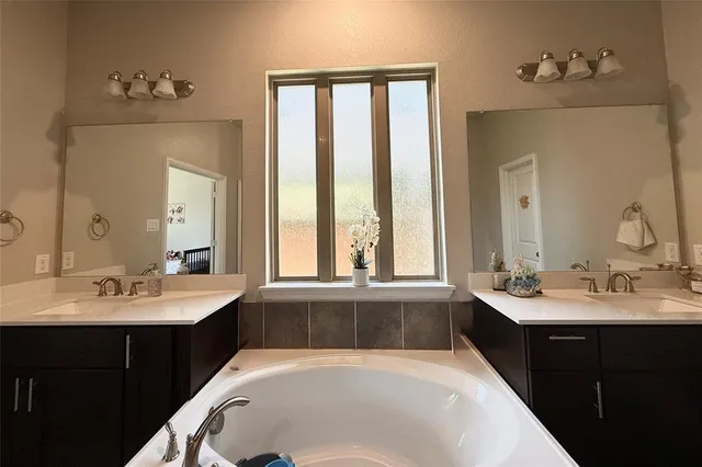 a bathroom with a tub sink and mirror