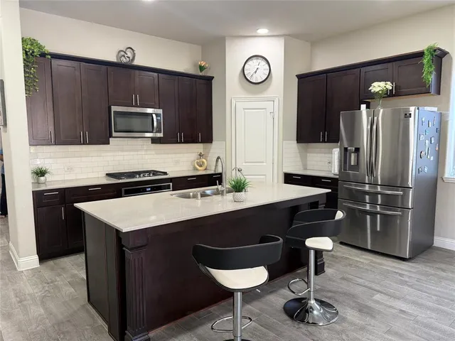 a kitchen with stainless steel appliances a sink a stove a refrigerator and cabinets