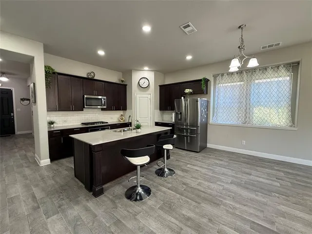 a kitchen with stainless steel appliances kitchen island granite countertop a sink refrigerator and cabinets