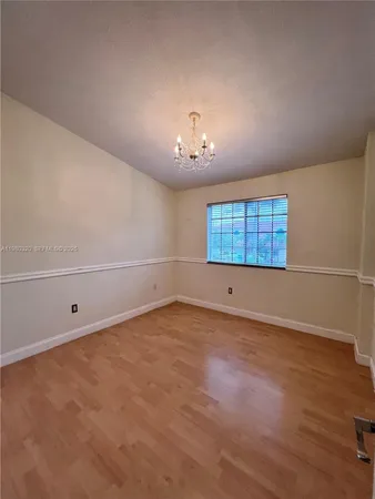 an empty room with chandelier fan and windows