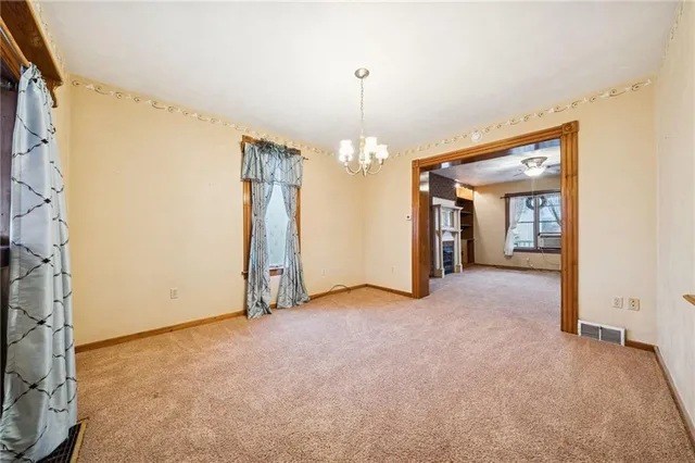 an empty room with chandelier fan and refrigerator