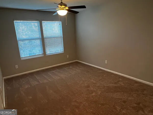 en empty room with windows and chandelier fan