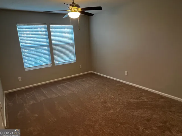 en empty room with windows and chandelier fan