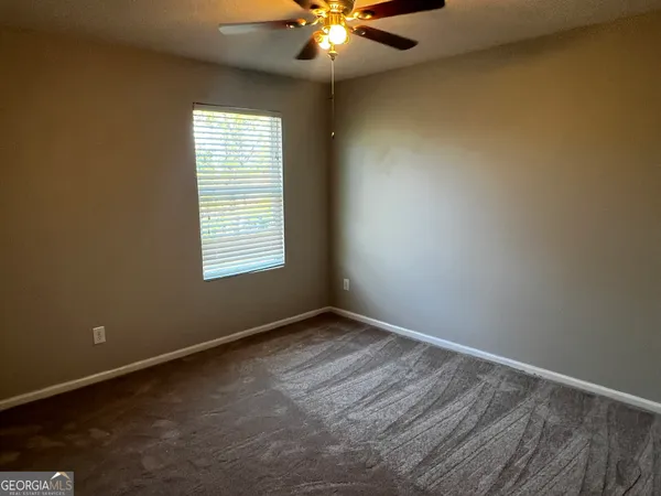 an empty room with window and chandelier fan