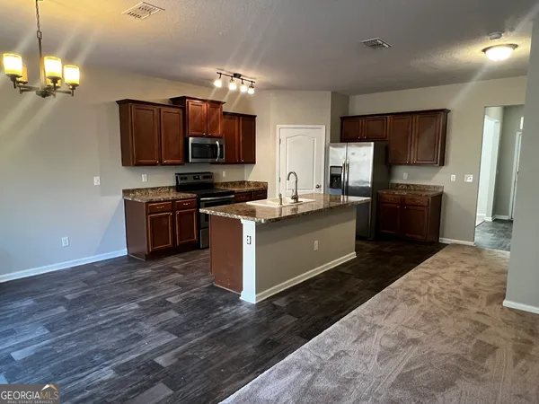 a kitchen with stainless steel appliances granite countertop a stove top oven a sink dishwasher a dining table and chairs with wooden floor