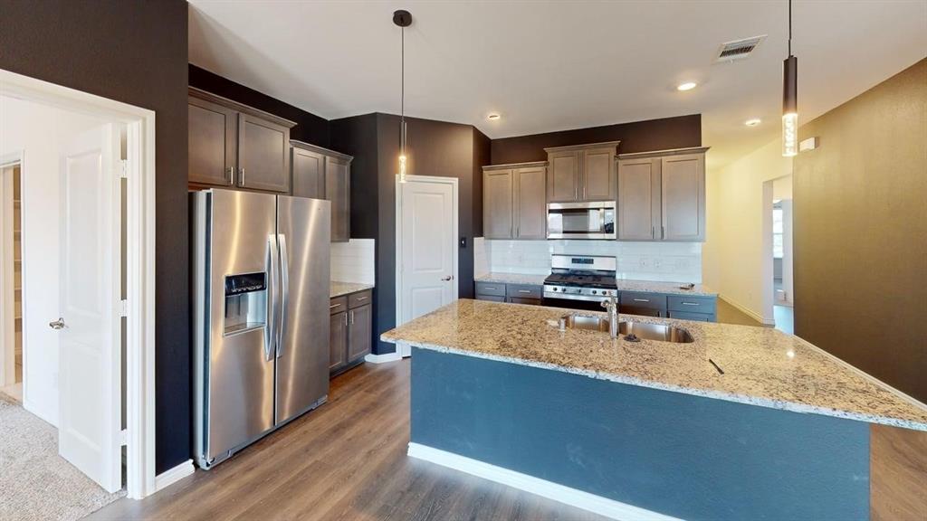 405 Rawhide Way Princeton, TX 75407 - Photo 5 of 22 a kitchen with stainless steel appliances granite countertop a refrigerator a stove and a sink with wooden floor