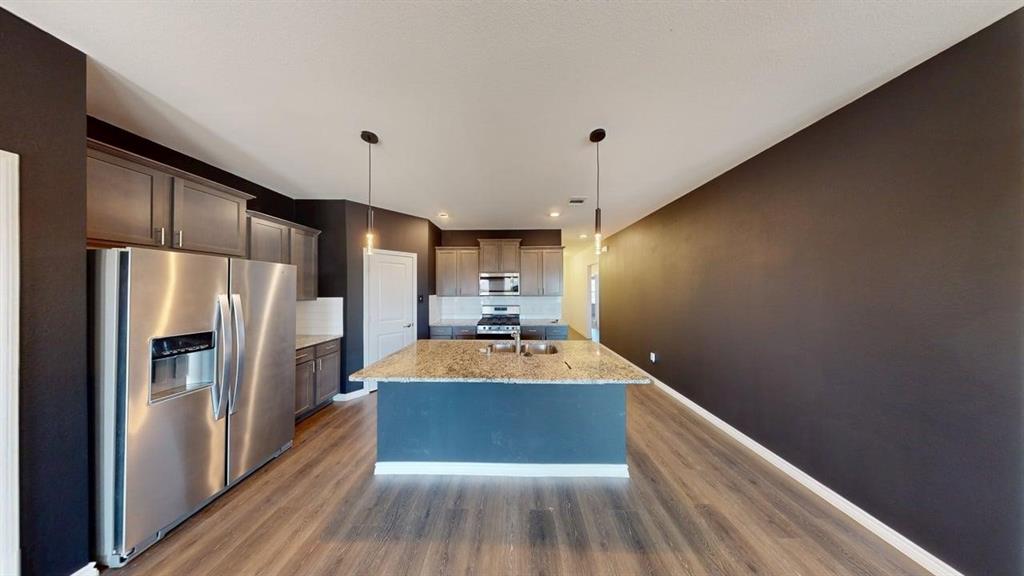 405 Rawhide Way Princeton, TX 75407 - Photo 6 of 22 a large kitchen with stainless steel appliances a large counter top space wooden floor and a refrigerator