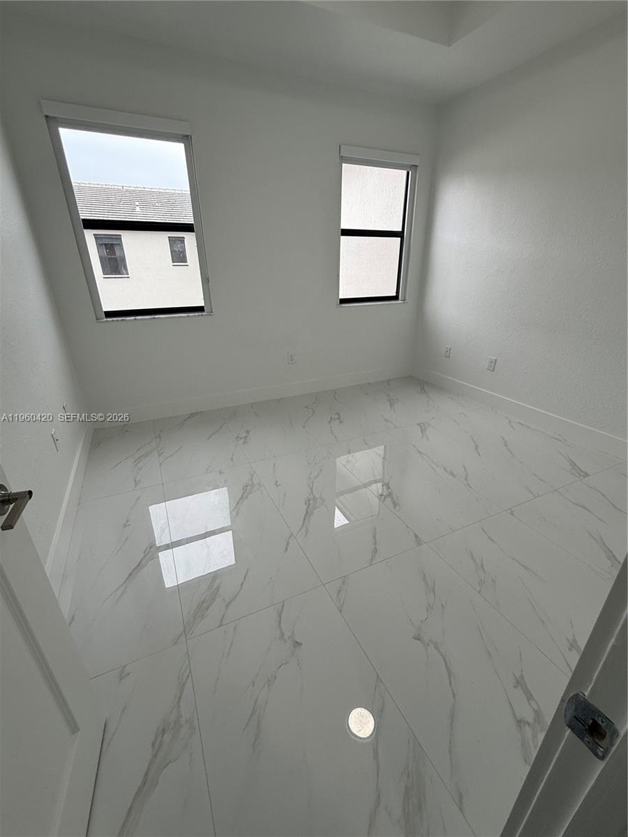 28519 Southwest 134th Court, Unit 28519 Homestead, FL 33033 - Photo 8 of 9 an empty room with windows and ceiling fan