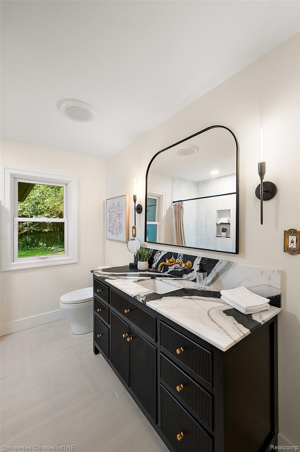 27331 Gardenway Road Franklin, MI 48025 - Photo 44 of 65 Double vanity featuring a black base with reeded accents and gold-toned hardware, topped with a striking black and white veined stone countertop