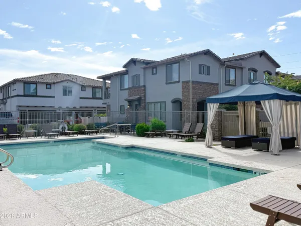 a view of a house with swimming pool and a chairs and tables in patio