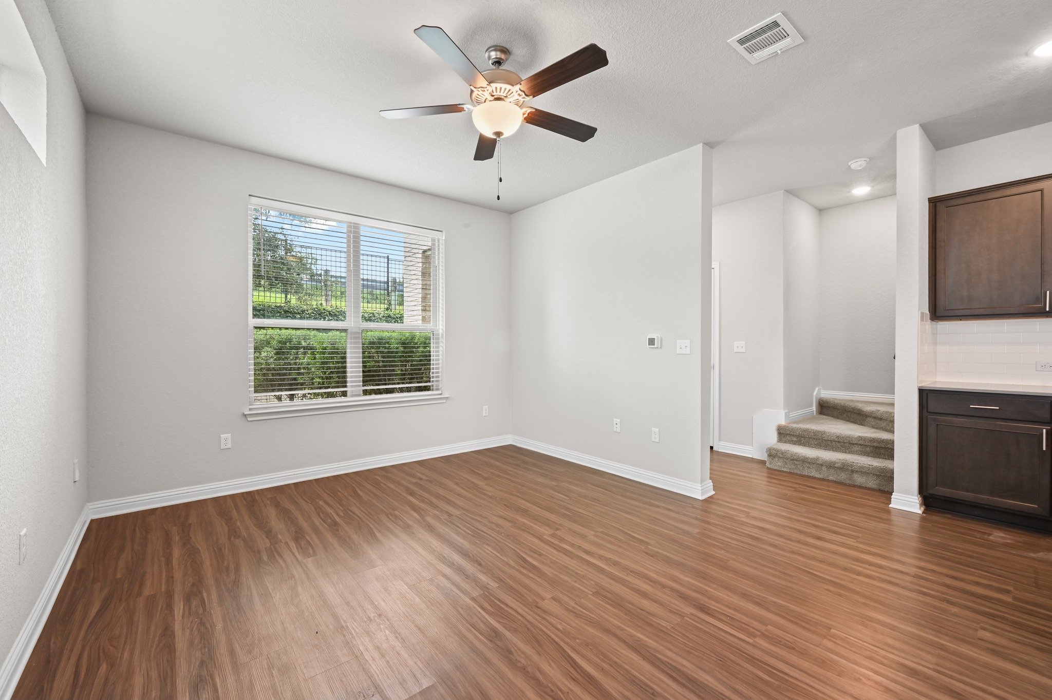 8201 Frida Bend Austin, TX 78744 - Photo 12 of 29 A well-lit living area features rich hardwood flooring and a functional ceiling fan.