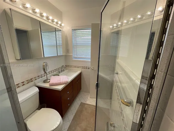 a bathroom with a sink a toilet a mirror and shower