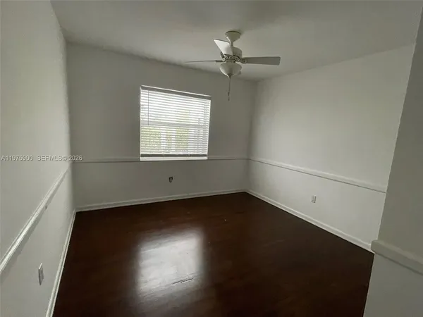 an empty room with wooden floor fan and windows
