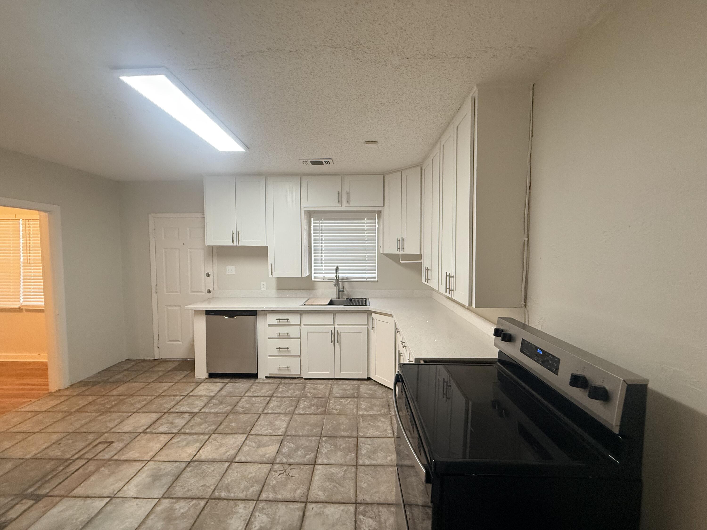 3418 25th Street Lubbock, TX 79410 - Photo 7 of 14 a kitchen with a sink a stove cabinets and wooden floor