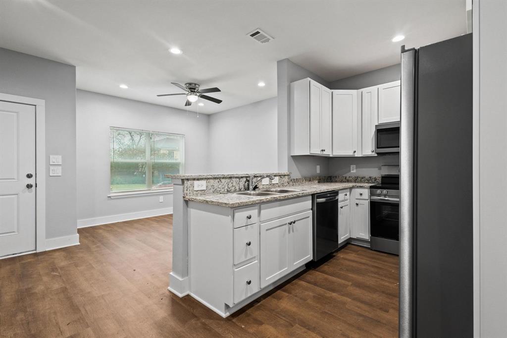 724 West Gandy Street Denison, TX 75020 - Photo 11 of 31 a kitchen with stainless steel appliances granite countertop a stove a sink and a refrigerator with wooden floors