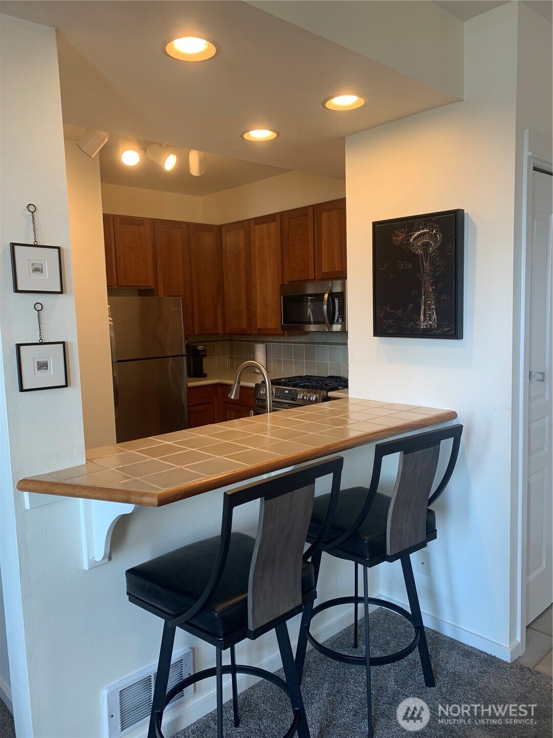 2000 Alaskan Way, Unit 342 Seattle, WA 98121 - Photo 16 of 40 a kitchen with stainless steel appliances granite countertop a table chairs sink and microwave