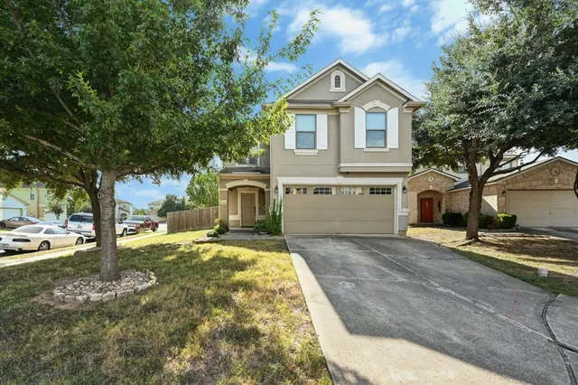 a view of a yard in front of a house with a large tree