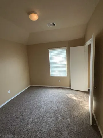 an empty room with windows & cabinet